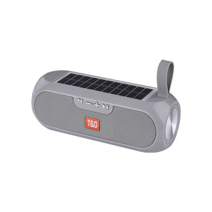 Image for solar powered waterproof outdoor bluetooth speaker in gray color. It has a silicone strap for carrying it around.