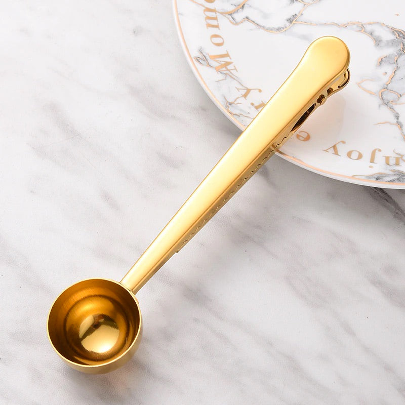 Image for gold color two-in-one stainless steel spoon and sealer placed on a plate.