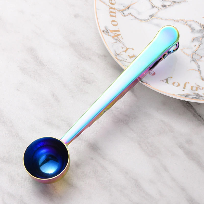 Image for rainbow color two-in-one stainless steel spoon and sealer placed on a plate.