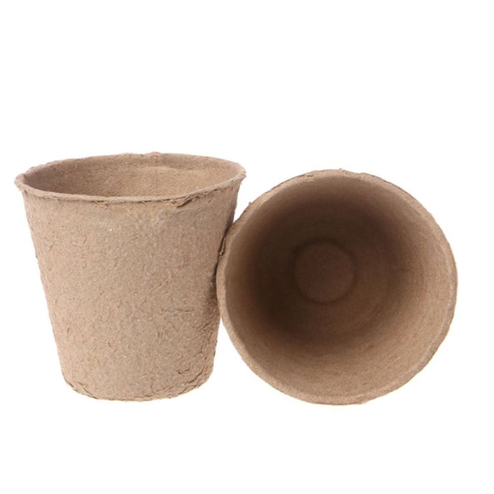 Image for two paper seed starter pots lying on the ground, with one placed upright and the other one on its side facing front.